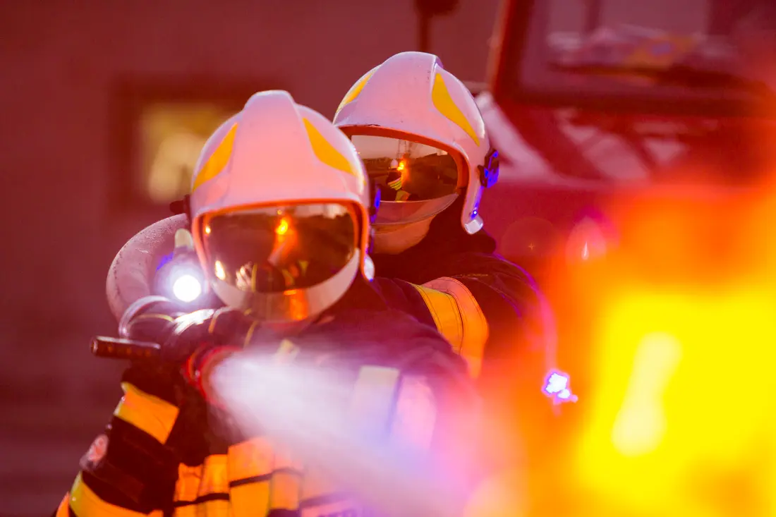 A firefighter in a helmet holding a hose nozzle